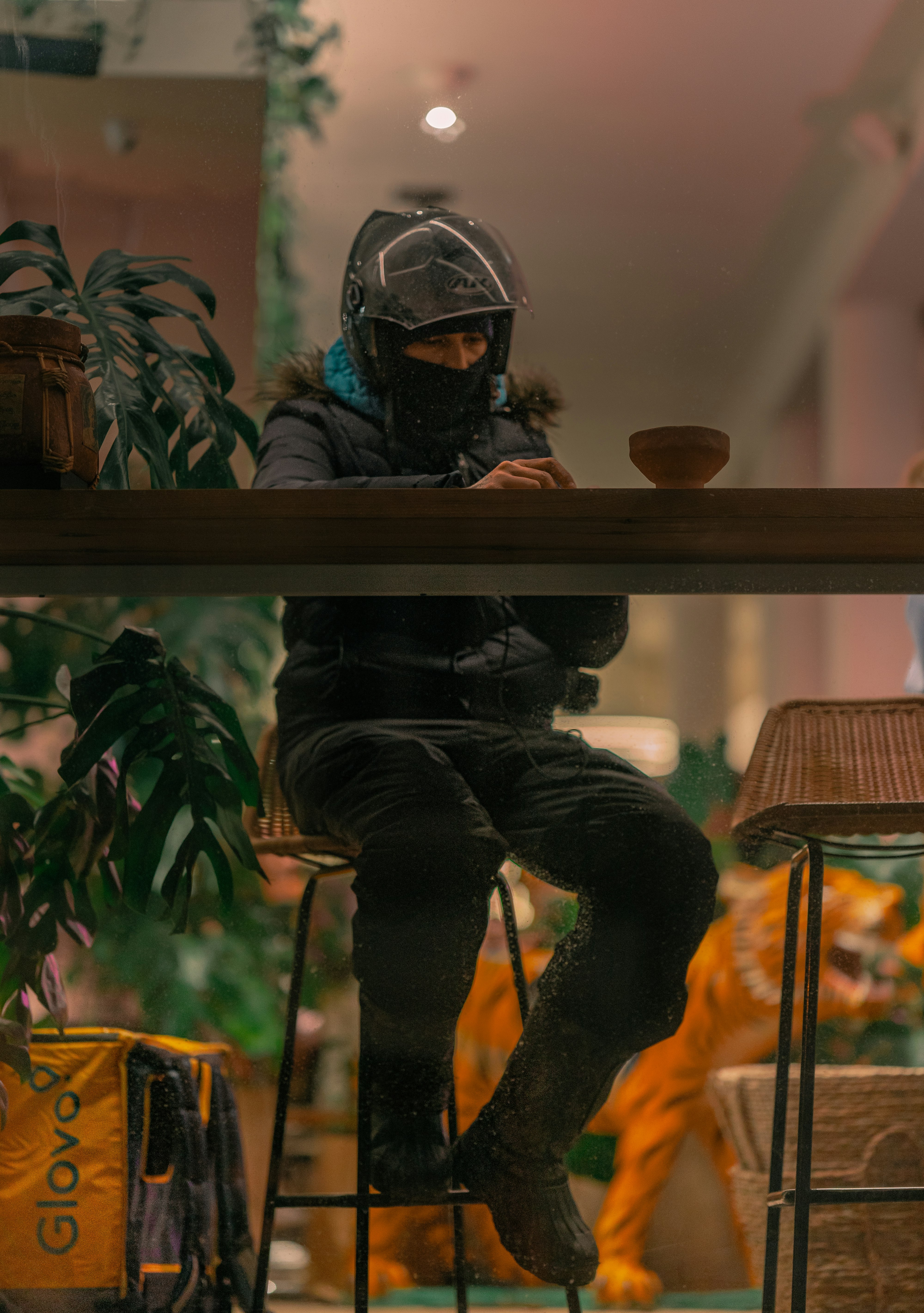 man in black jacket wearing helmet sitting on brown wooden table